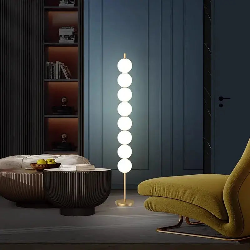 Modern brass floor lamp with six glowing white spheres on a slender gold-toned stand for elegant living room decorbites brass floor lamp