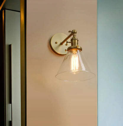 Modern brass funnel glass wall lamp with clear conical shade and exposed filament bulb for elegant bedroom lighting decorbites funnel glass