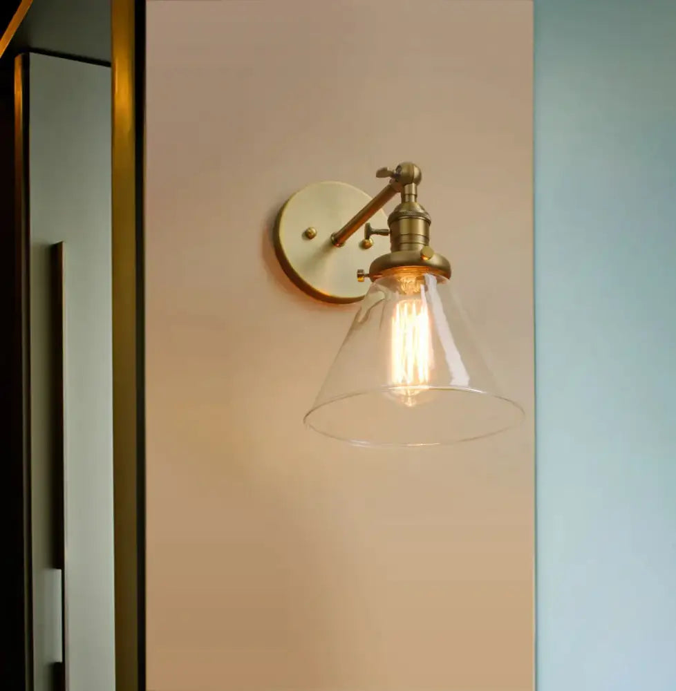 Modern brass funnel glass wall lamp with clear conical shade and exposed filament bulb for elegant bedroom lighting decorbites funnel glass