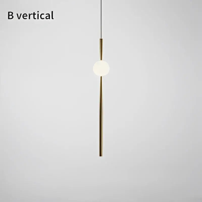Modern brass geometric glass pendant light featuring a sleek vertical rod and glowing bulb for dining room use