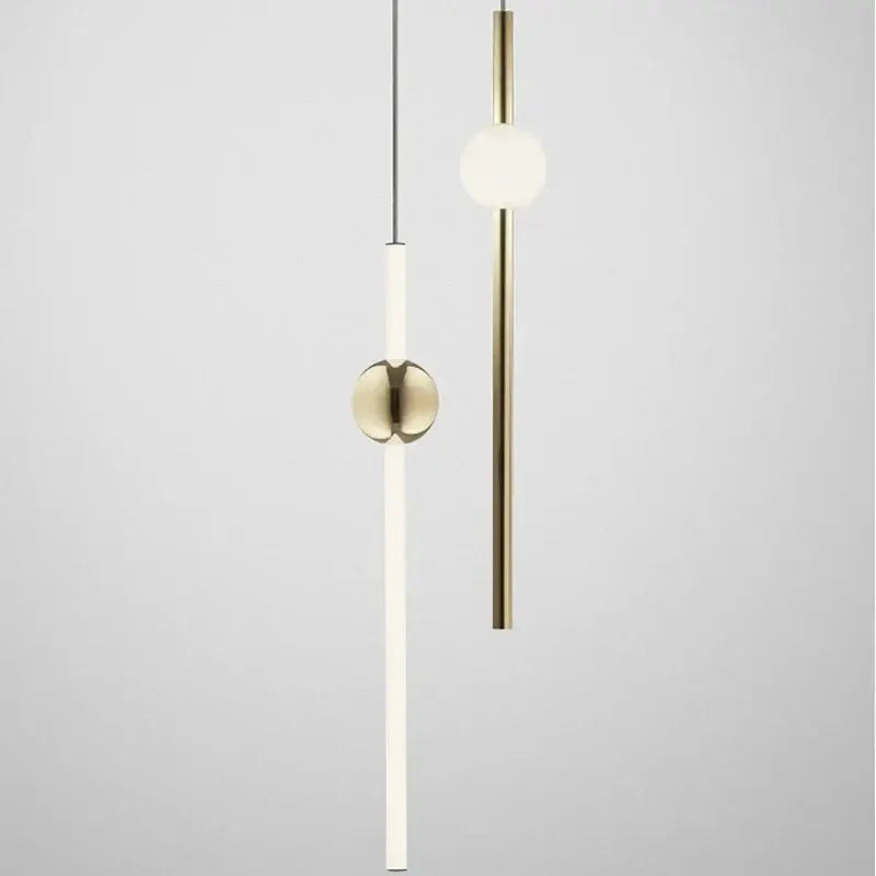 Two minimalist modern brass glass pendant lights with slender cylindrical bodies and spherical globes for dining room