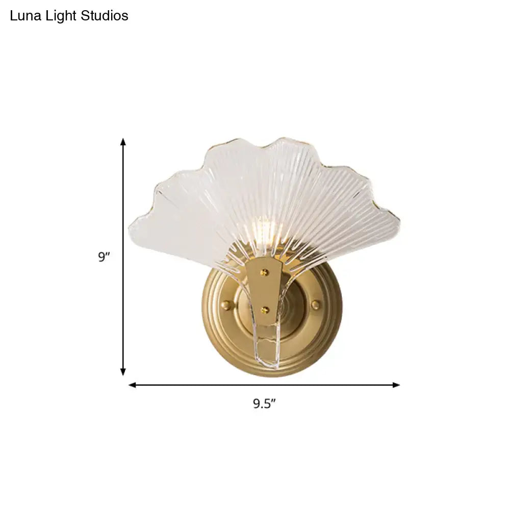 Modern brass ginkgo leaves wall light with a translucent glass fan-shaped shade and brushed brass mounting plate