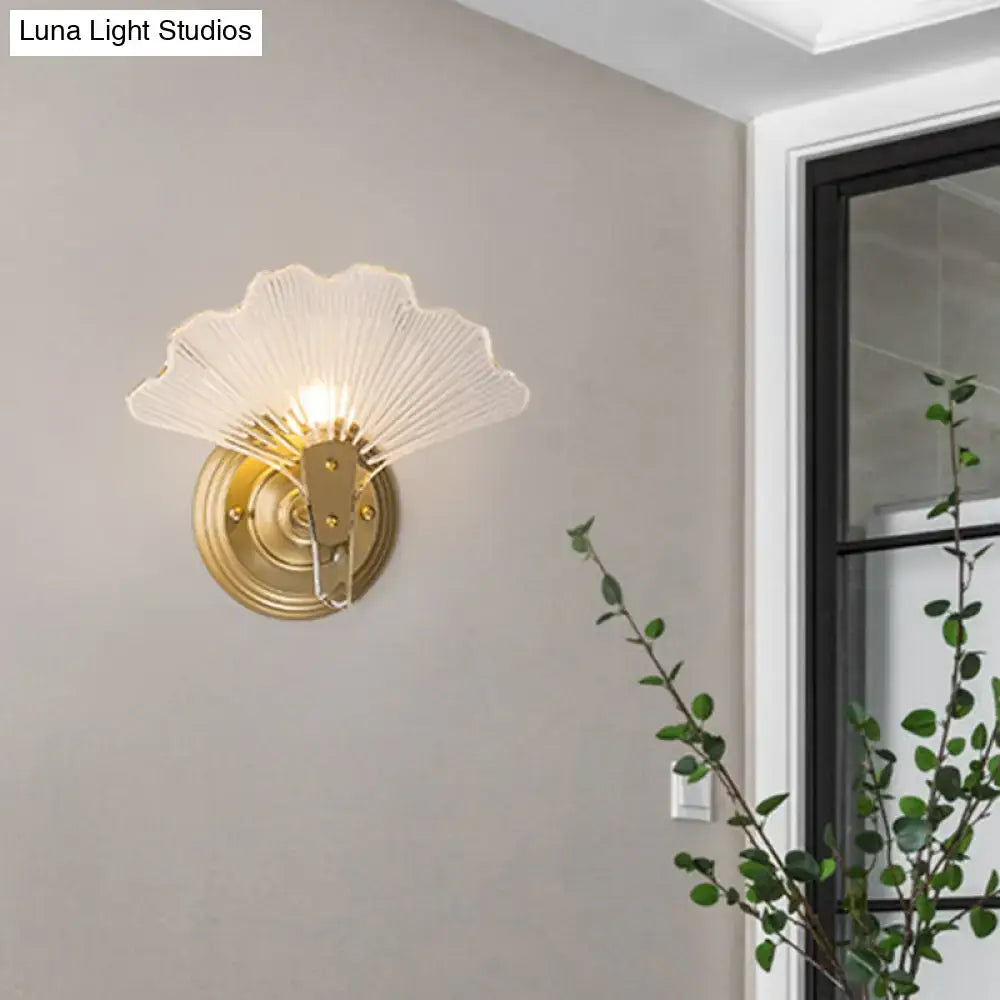 Modern brass ginkgo leaves wall light with gold-toned metal and translucent fan-shaped glass shade for bedroom use