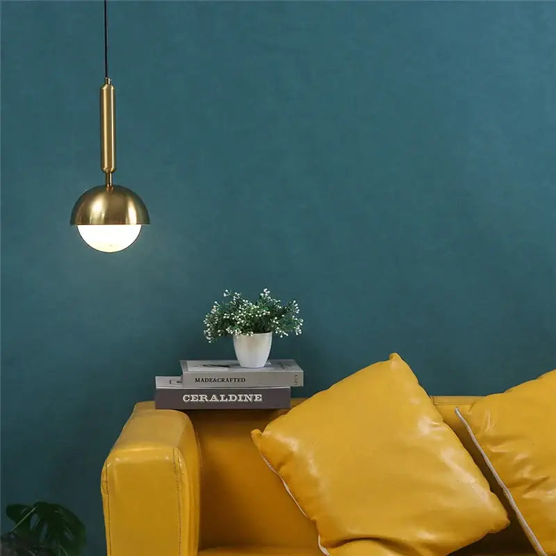 Modern brass glass ball led pendant chandelier with spherical shade hanging above mustard-yellow leather sofa decorbites pendant chandelier