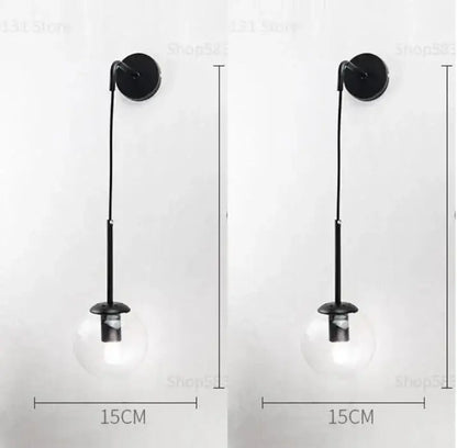 Black wall light with decorbites glass ball led clear globe and slender metal stem for modern bedroom sconce decor