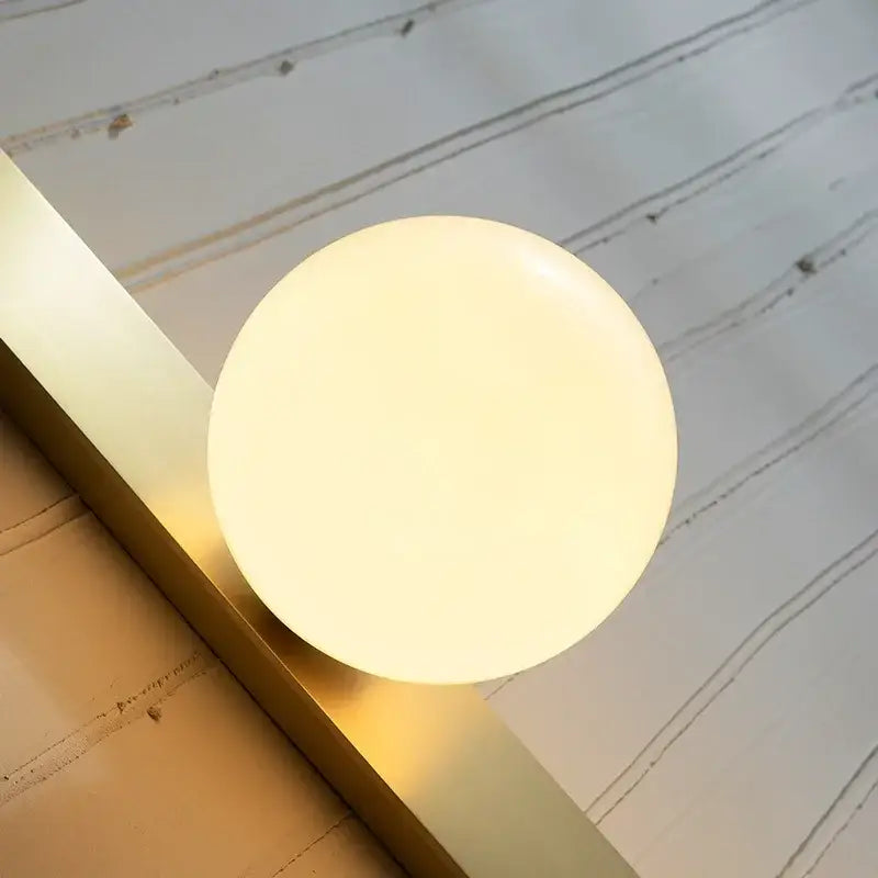 Modern brass glass ball led wall sconce with an ivory frosted glass globe and polished brass base for bedroom decorbites wall sconce
