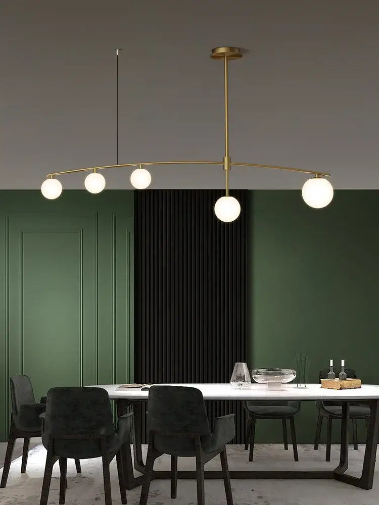 Modern brass glass ball pendant chandelier with five white glass bulbs arranged in an elegant curved arc for dining room decorbites glass ball