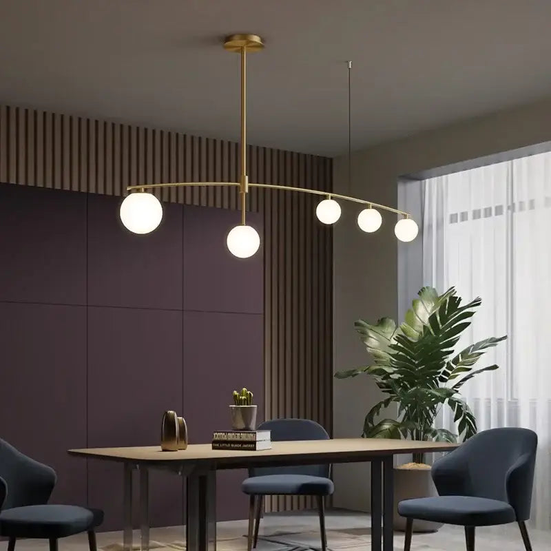 Modern brass glass ball pendant chandelier with five white glass bulbs in a gold-toned arc for dining room decorbites glass ball