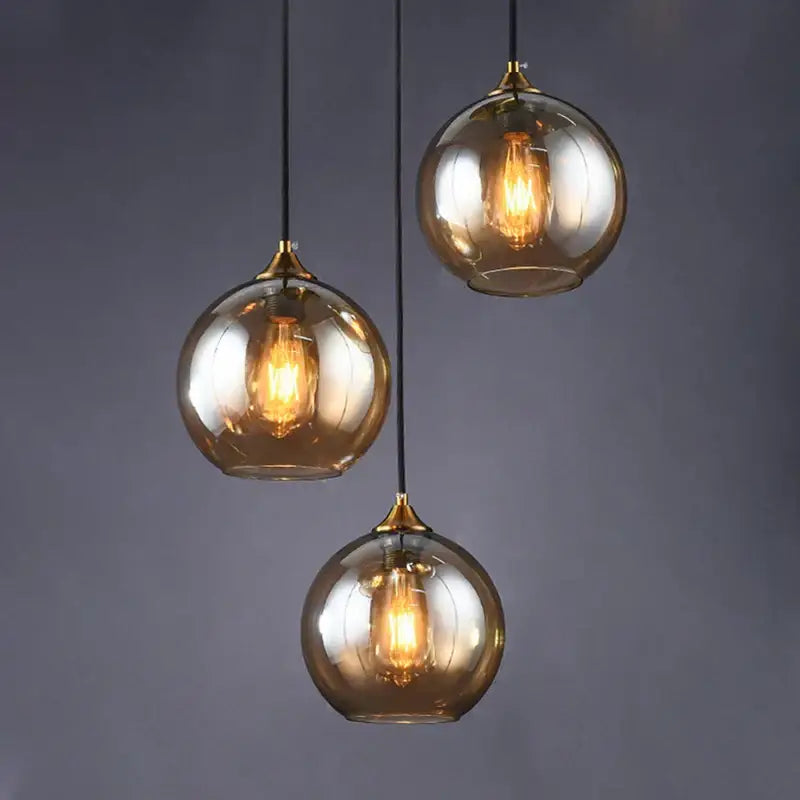 Three spherical amber glass ball pendant lights with brass accents and exposed filament bulbs for modern decorbites pendant light fixtures