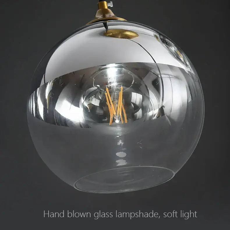 Modern brass glass ball pendant light with a transparent hand-blown glass globe and exposed filament bulb for dining decorbites decor