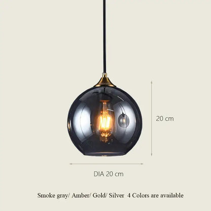 A sleek smoke gray decorbites glass ball pendant light with brass accent and exposed filament bulb for dining and kitchen