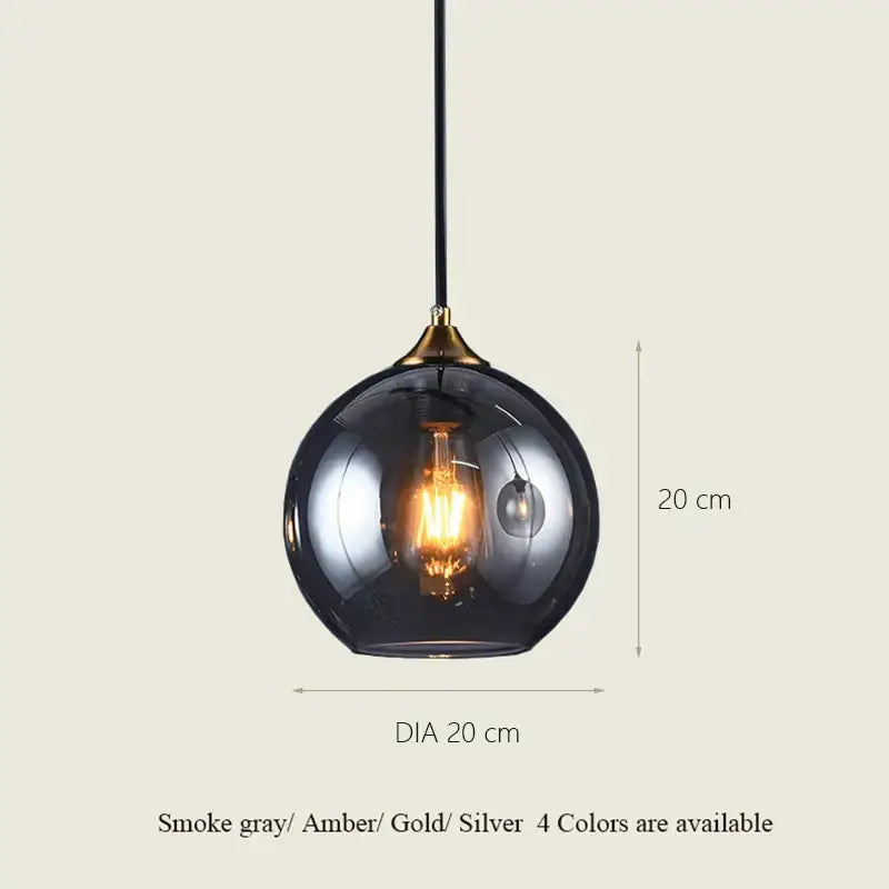 A sleek smoke gray decorbites glass ball pendant light with brass accent and exposed filament bulb for dining and kitchen