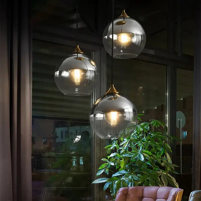 Three spherical glass ball pendant lights with brass fixtures and warm bulbs for modern dining and kitchen decorbites pendant light