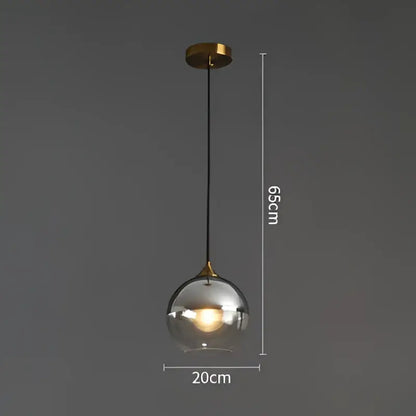 Modern brass glass ball pendant light with a spherical glass shade brass mount and black cord for dining and kitchen decorbites
