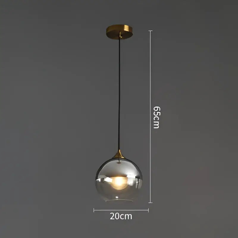 Modern brass glass ball pendant light with a spherical glass shade brass mount and black cord for dining and kitchen decorbites