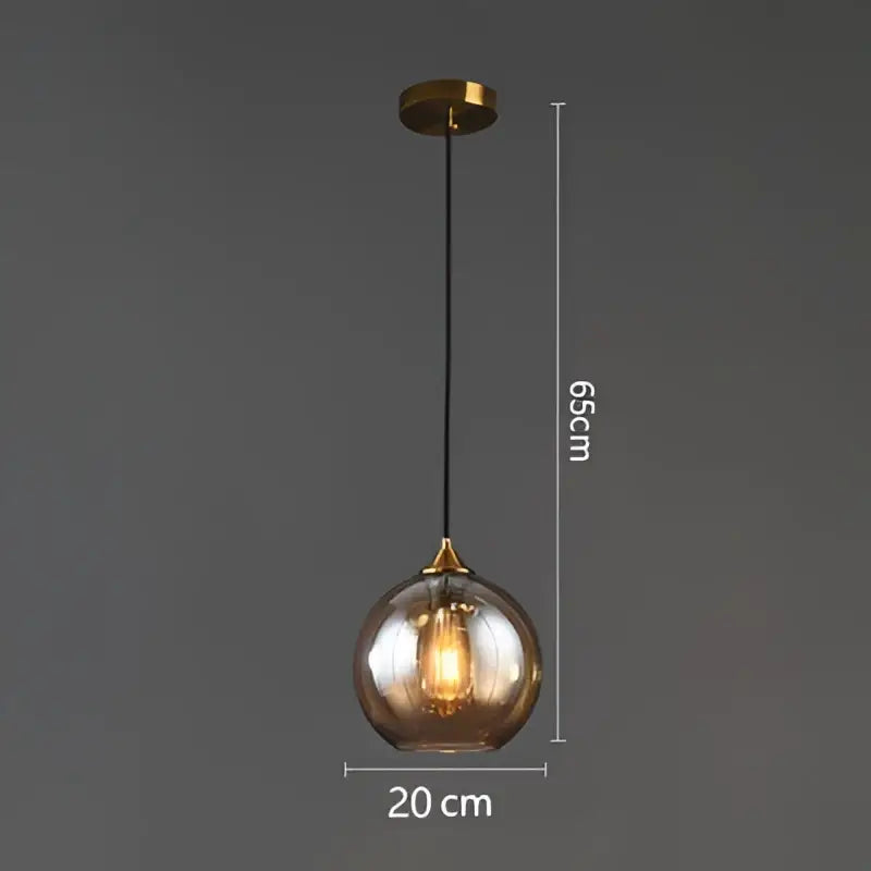 A sleek spherical amber glass ball pendant light with brass finish and black cord for modern dining and kitchen decorbites
