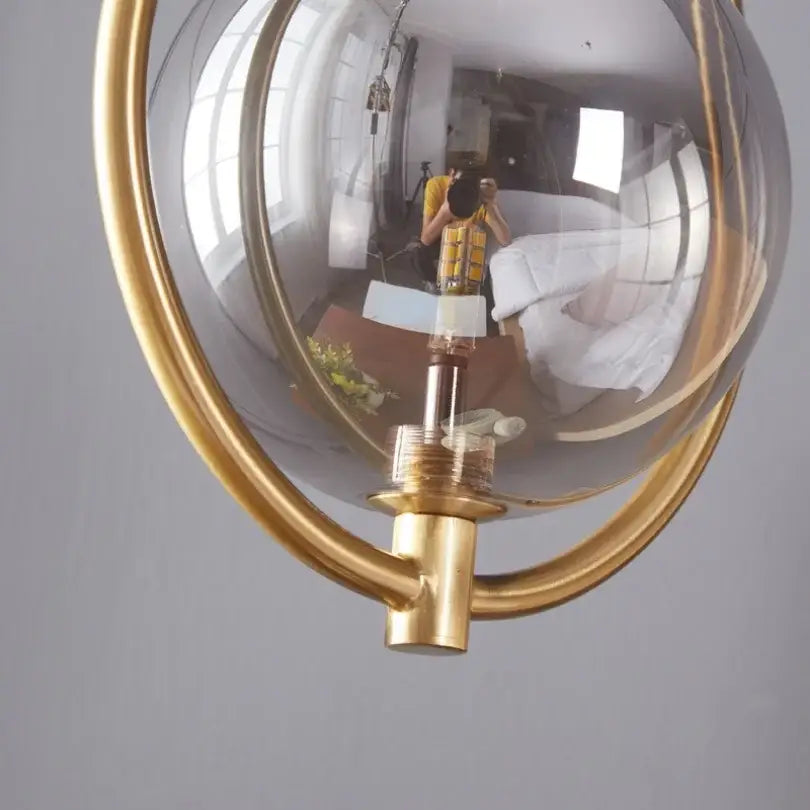 Gold-toned modern brass glass ball pendant lighting with clear glass globe and brass hardware for bedroom decorbites glass ball