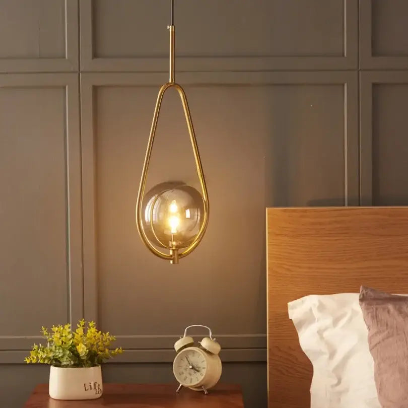 A modern brass glass ball pendant lighting with a teardrop frame and clear globe for bedroom decorbites glass ball