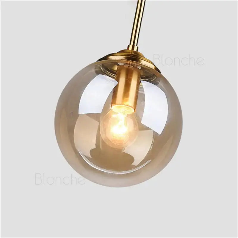 Modern brass glass ball pendant lights featuring warm-toned amber glass globe and brass fixture with exposed bulb for decorbites glass ball pendant