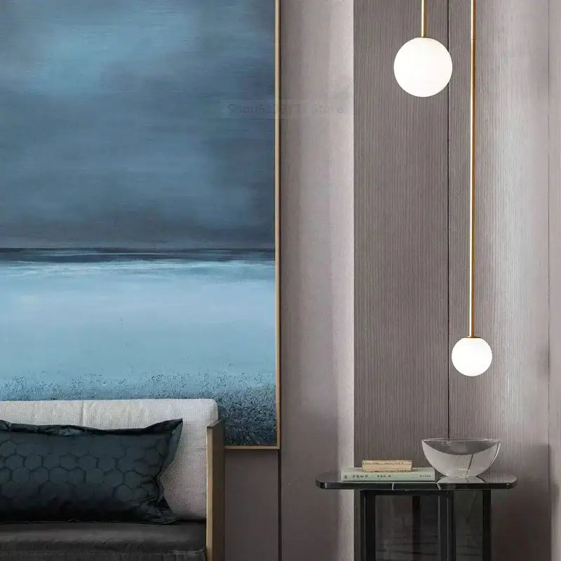 Two spherical white frosted glass ball pendant lights with slender gold-toned rods for modern dining room decorbites