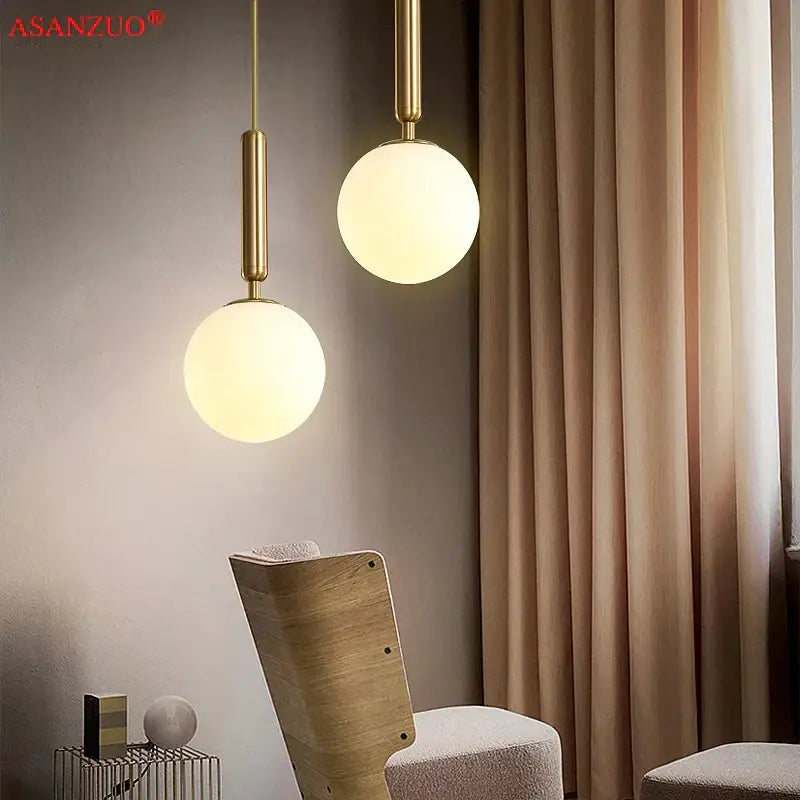 Two elegant brass-finished glass ball pendant lights with frosted globe shades for modern kitchen decor by decorbites brass glass