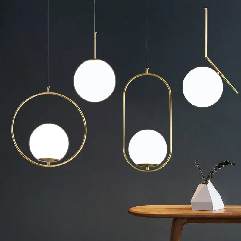 Modern brass glass ball pendant lights with gold-toned geometric frames and glowing white spherical shades for kitchens