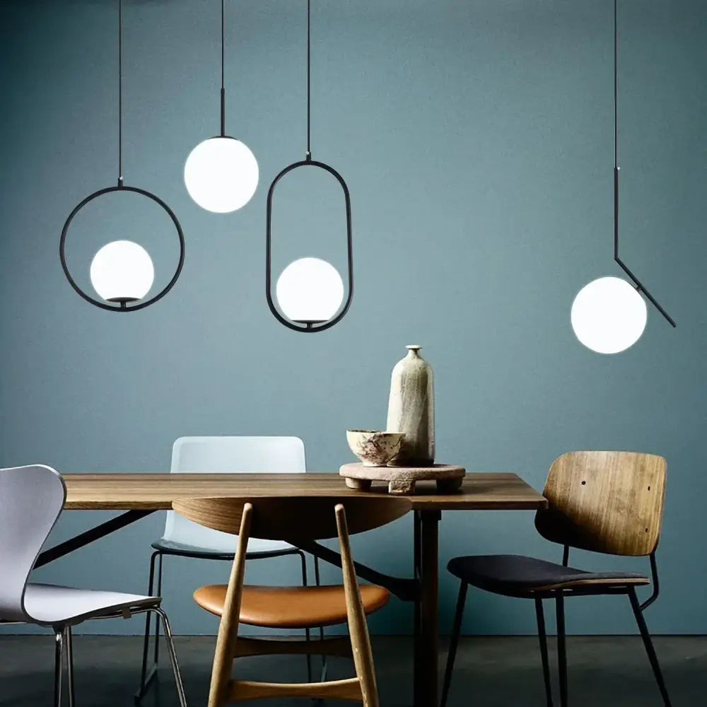 Modern brass glass ball pendant lights with sleek black metal frames and glowing white glass ball shades for kitchen decorbites