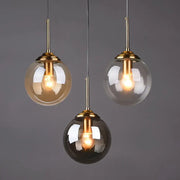 Modern brass glass ball pendant set with three globe lights featuring warm filament bulbs for bedroom lighting decorbites glass ball