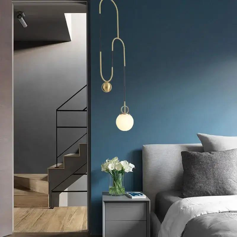 Modern brass pendant light with curved sculptural design and two glass ball pulley shades for dining room decorbites