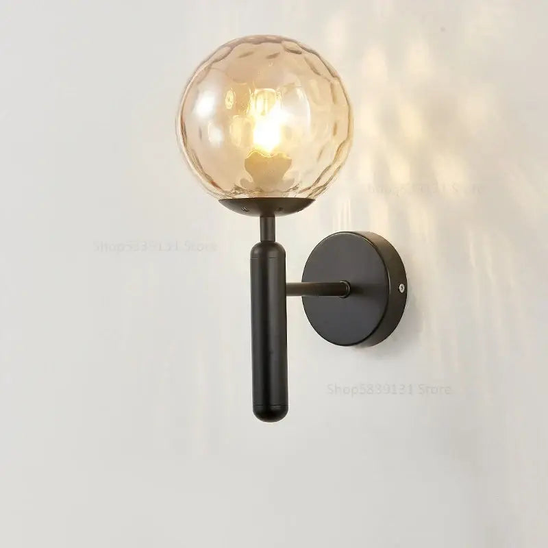 Modern black metal wall lamp with textured amber glass ball globe from decorbites glass ball wall collection for bedroom decor