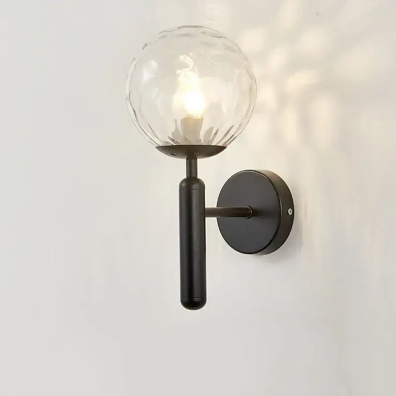 Black metal wall lamp with textured clear glass globe from decorbites glass ball collection for modern bedroom decor