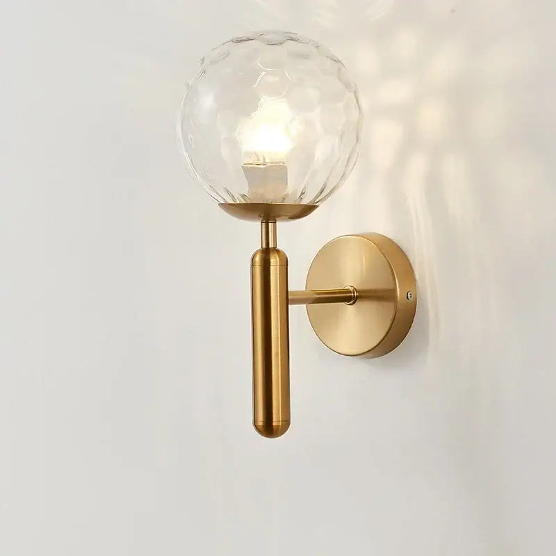 Modern brass glass ball wall lamp with gold-toned sconce and textured clear glass globe for bedroom decorbites wall lamp