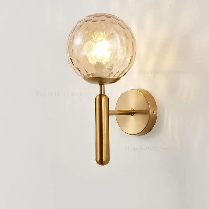 Modern brass glass ball wall lamp with gold-toned metal and textured amber-hued glass globe for bedroom decorbites wall lamp