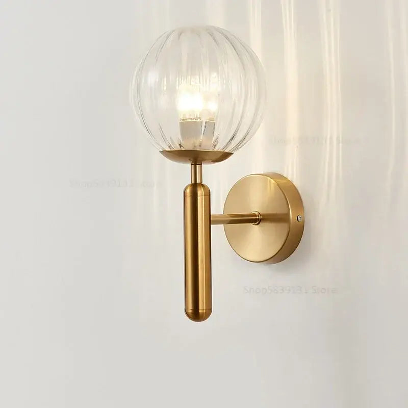 A modern brass wall lamp with a ribbed opaque glass ball and cylindrical stem for bedroom decorbites glass ball wall use