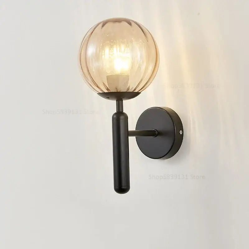 A sleek black metal wall lamp with a warm amber glass ball globe for modern decorbites glass ball wall lighting