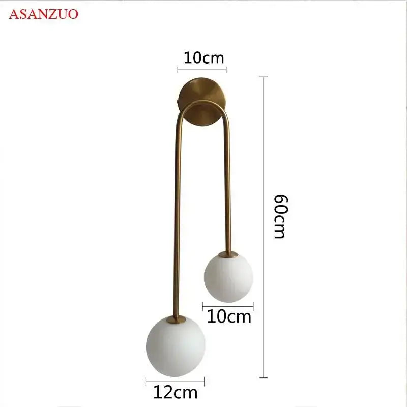 Modern brass glass ball wall sconce with two white glass ball shades on a curved decorbites brass glass arm for bedroom use