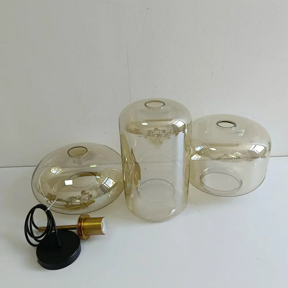 Set of three smoked glass pendant lamp shades with brass-finished bulb holders in a modern decorbites glass chandelier