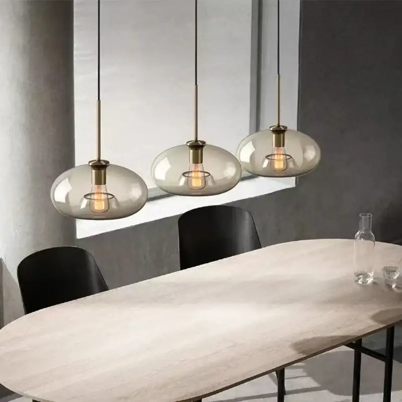 Three modern pendant lights with frosted glass domes and brass accents in a decorbites glass chandelier above dining table