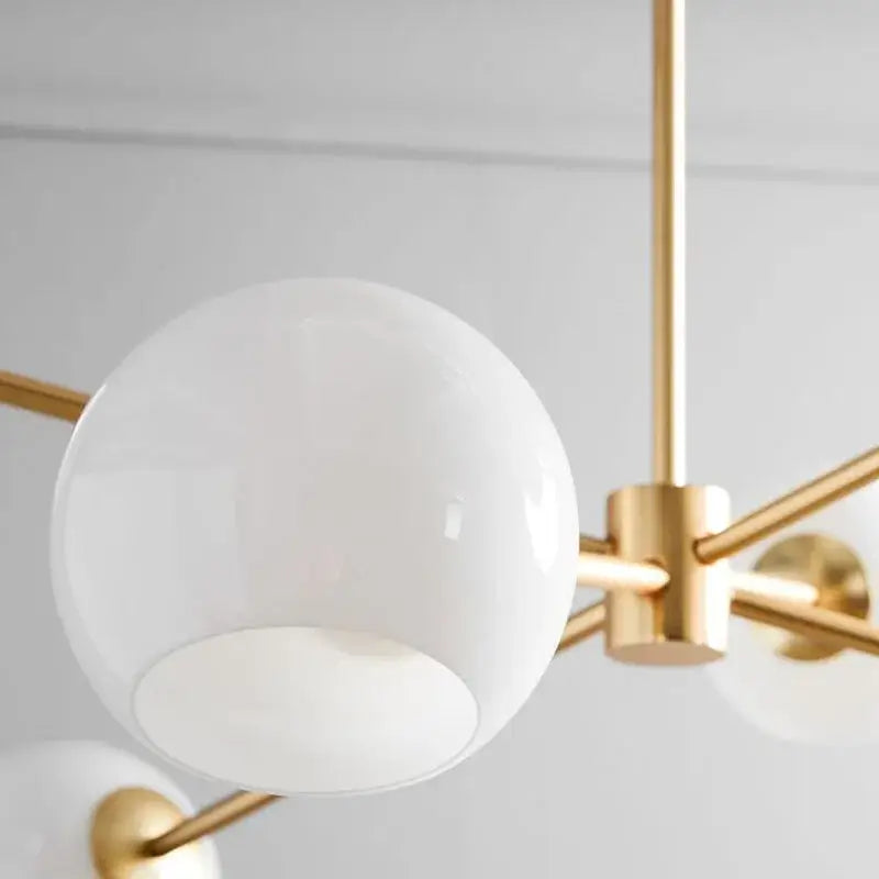 Modern brass glass chandelier with a large white glass shade and polished brass arms for dining room and living spaces