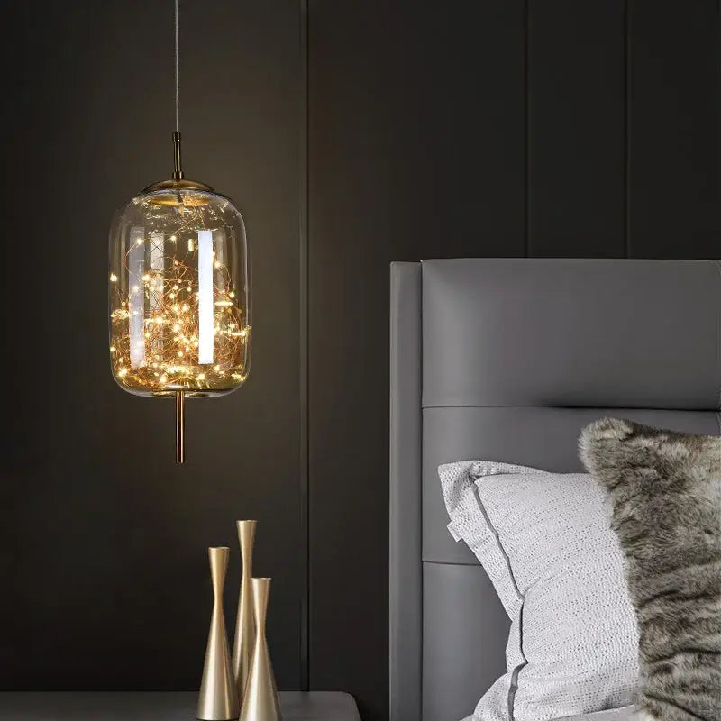 Modern brass glass cord pendant light with clear jar-shaped shade and warm filament string lights for dining room use