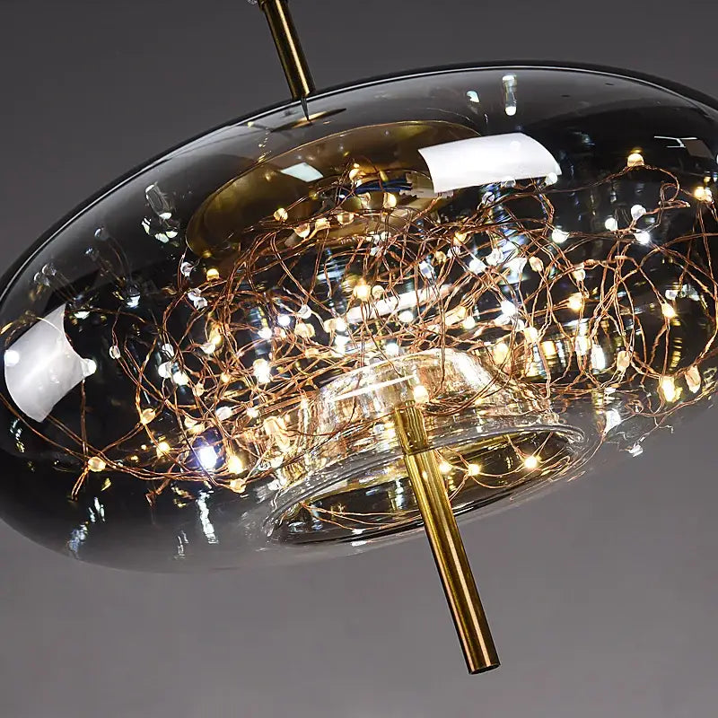 Modern brass glass cord pendant light with a sleek dark glass dome and copper wire warm led string lights in iron finish
