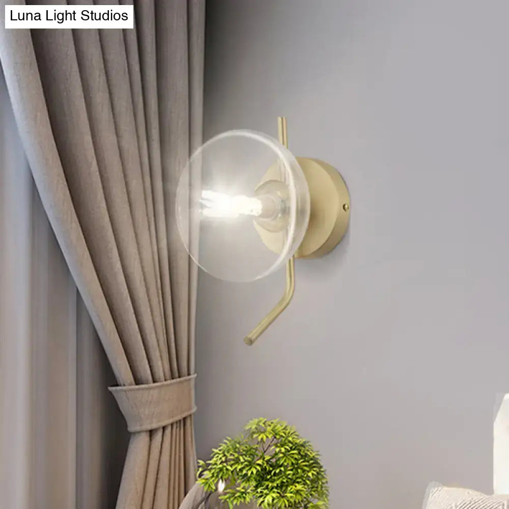 Modern brass glass dome wall sconce with gold arm and clear glass dome shade for bedroom lighting