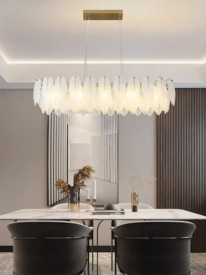 Modern brass glass feather chandelier with translucent white feather shades suspended from gold ceiling mount for dining room