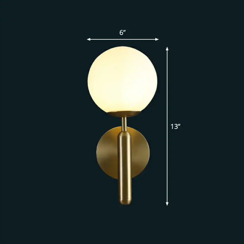 Modern brass glass globe wall mount light featuring a gold finish and frosted spherical glass for living room use