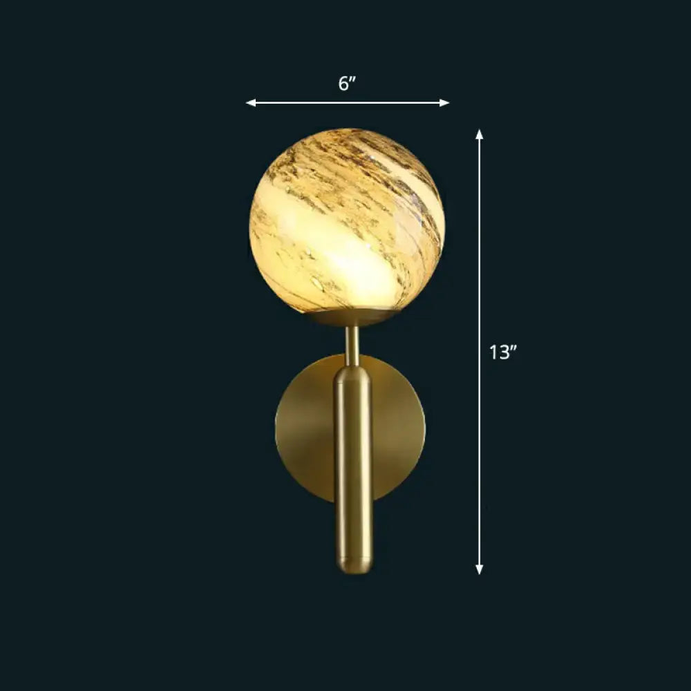 Modern brass glass globe wall mount light with gold-toned spherical sconce and warm marbled glass globe for living room