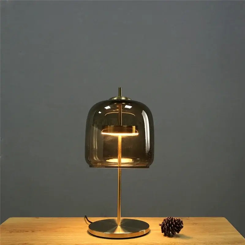 A modern brass glass lampshade led table lamp with smoked glass dome and brass base for bedroom decor