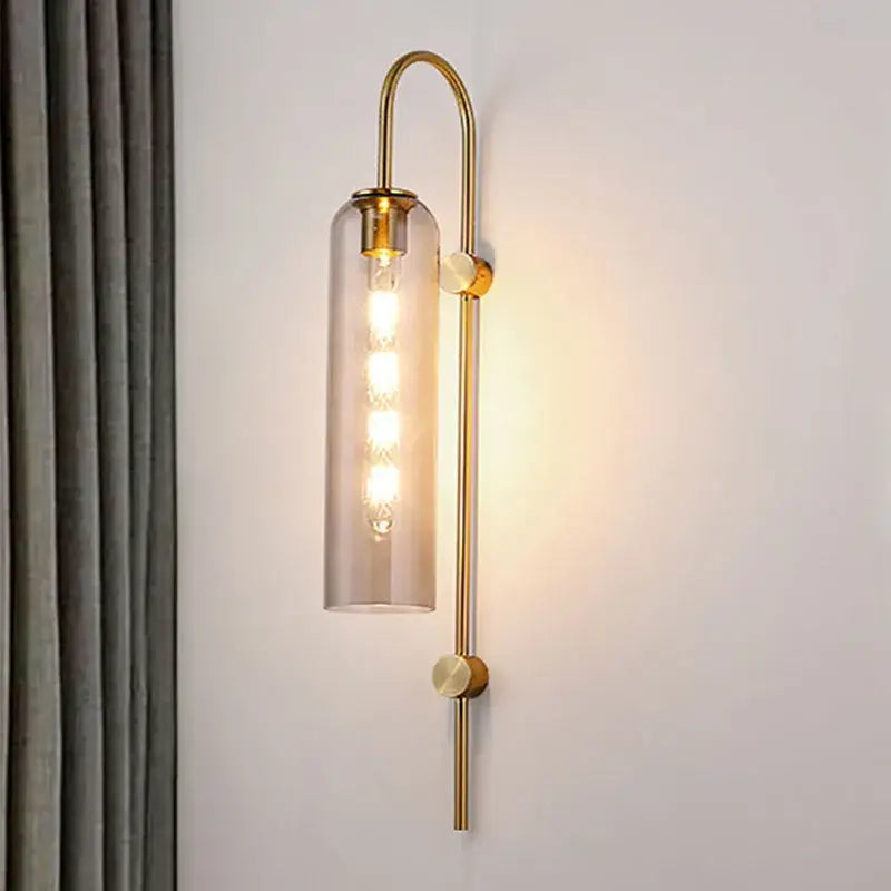 Modern brass glass sconce wall lamp featuring a gold-toned wall lamp with cylindrical smoked glass shade and filament bulb