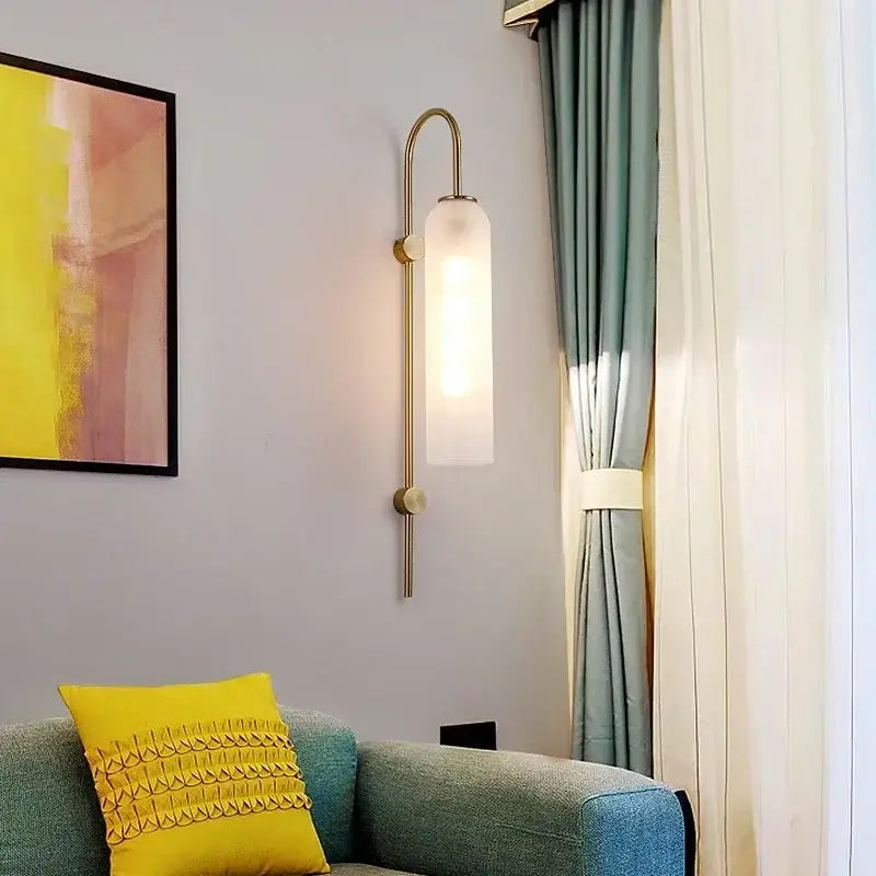 A sleek modern brass wall lamp with a frosted glass sconce wall shade for living room lighting