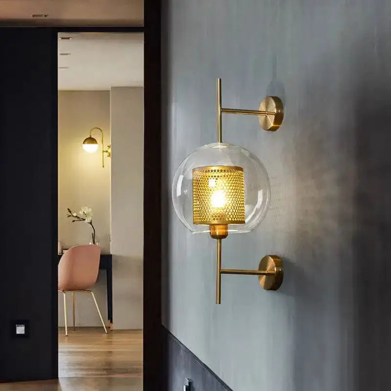 Modern brass glass wall lamp featuring a gold-toned perforated mesh shade and clear glass globe for bedroom decorbites brass glass sconce