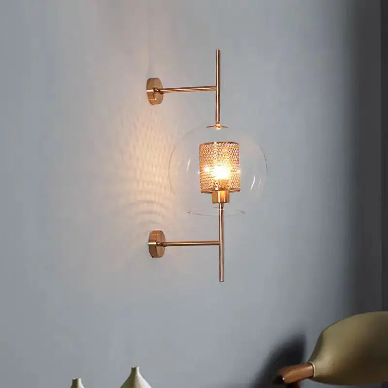 Modern brass glass wall lamp with gold-toned perforated brass shade and clear glass globe for bedroom decorbites brass glass sconce